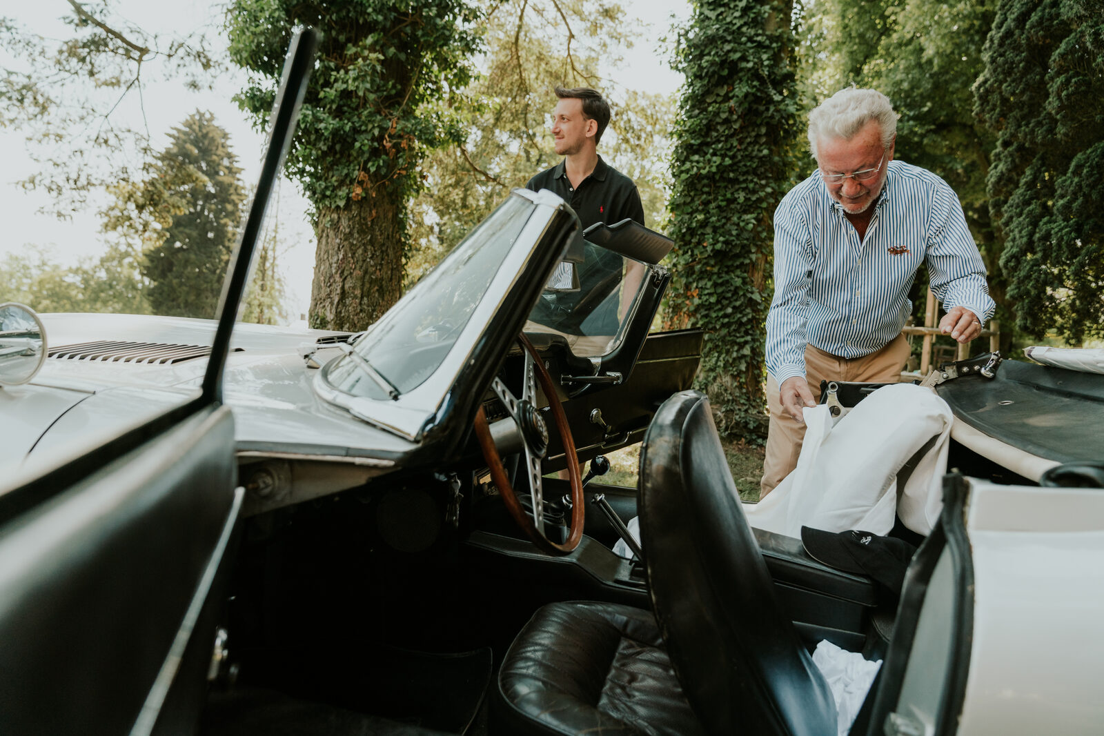 Zwei Gäste am offenen Cabrio im Park des Hotels