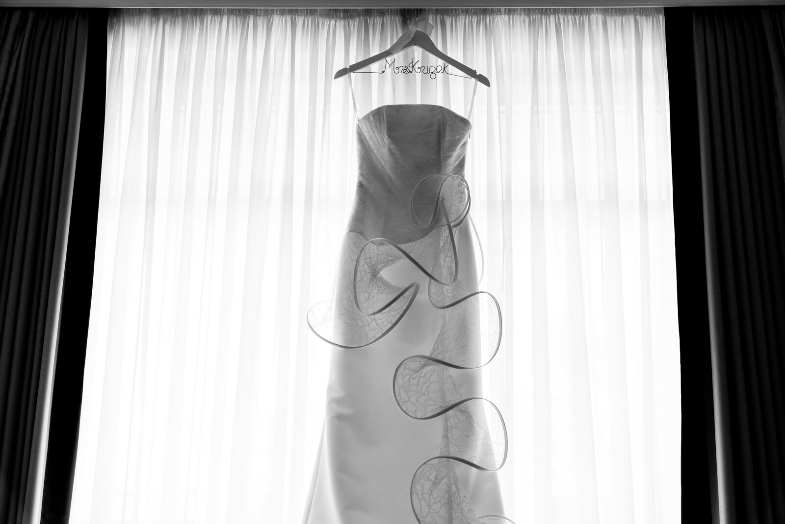 Das Brautkleid hängt am Bügel vor dem Fenster — Schwarz-Weiß