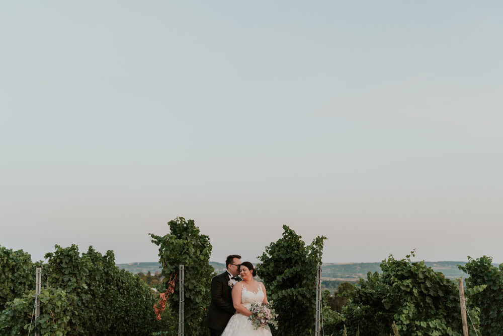 Das Brautpaar geht Hand in Hand durch die Weinberge